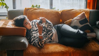 A teen scrolls through social media alone on her phone.